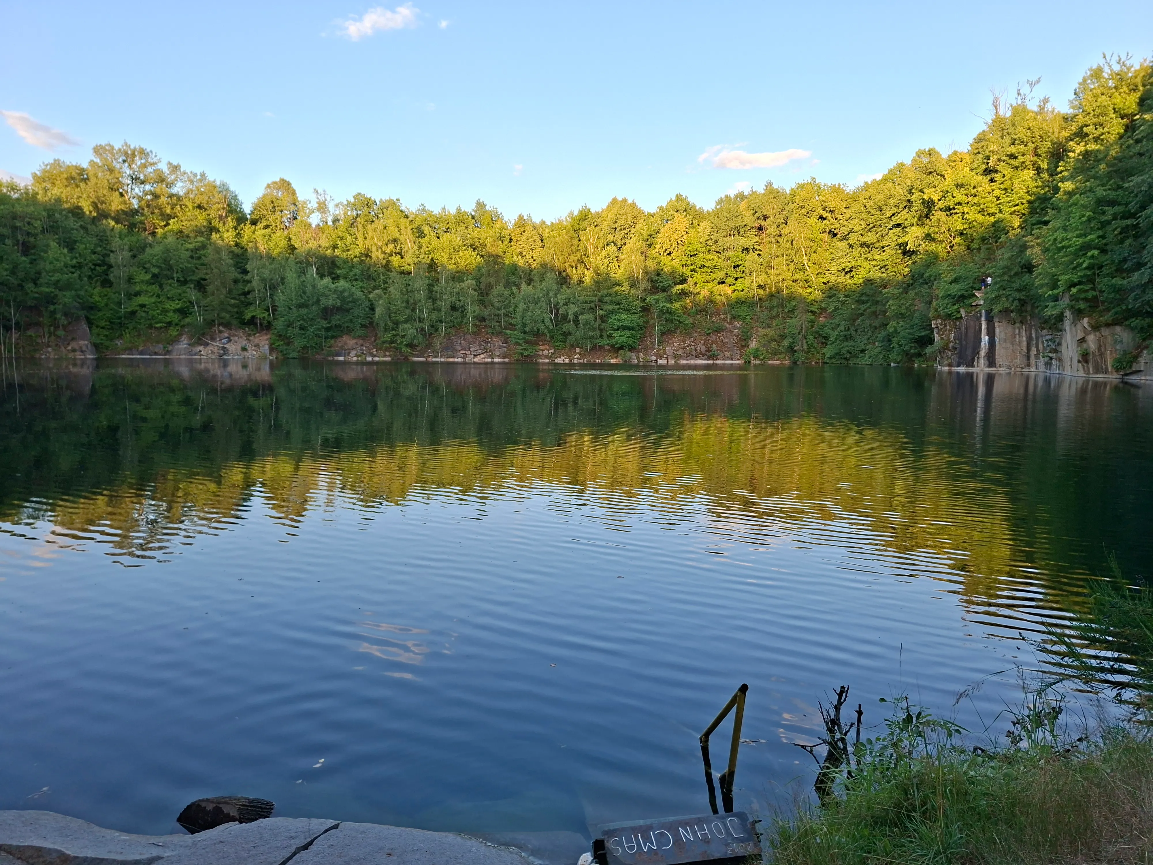 Submerged quarry with small ladder leading to water in foreground